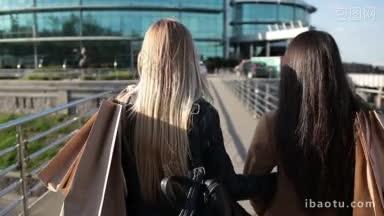 特写的背影，两个美丽的长发女人拿着购物袋在他们的肩膀上步行桥